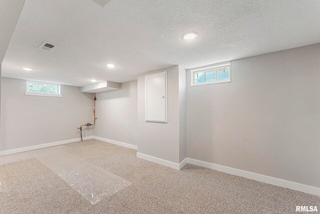 below grade area with a textured ceiling, light colored carpet, recessed lighting, and baseboards
