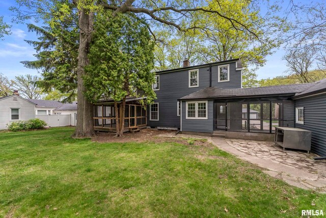 back of property with a sunroom, a chimney, a patio, and a shingled roof