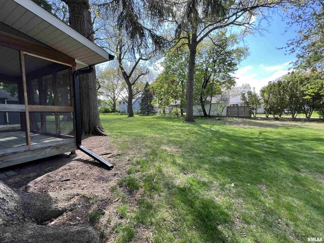 view of grassy yard with a sunroom