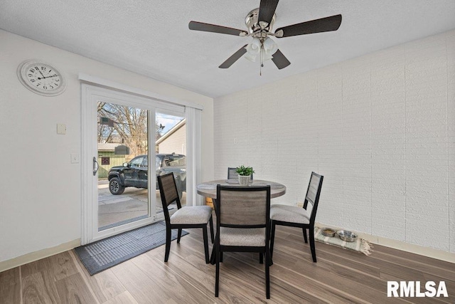 dining room with a textured ceiling, baseboards, a ceiling fan, and wood finished floors