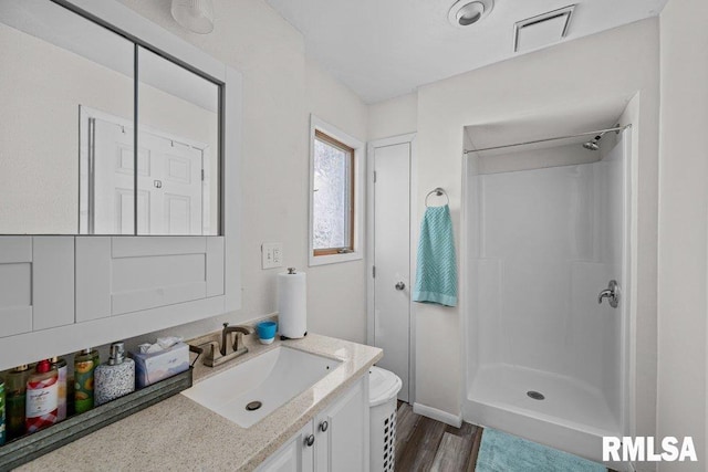 bathroom with vanity, toilet, wood finished floors, and a stall shower