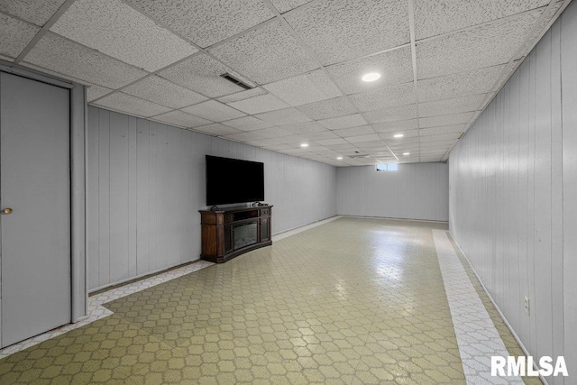 finished basement with recessed lighting, visible vents, tile patterned floors, wood walls, and a paneled ceiling