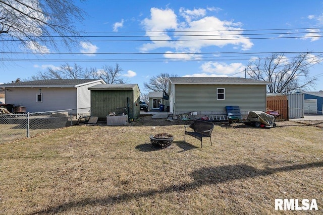 back of property with an outdoor fire pit, an outbuilding, fence, and a shed