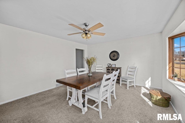 dining room featuring light carpet, baseboards, and ceiling fan