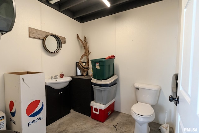 bathroom featuring toilet, vanity, and concrete flooring