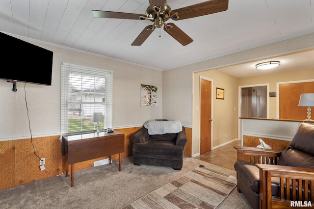 living room featuring wainscoting, ceiling fan, crown molding, wood walls, and carpet floors