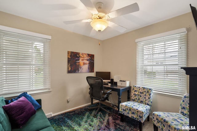carpeted office space featuring ceiling fan and baseboards