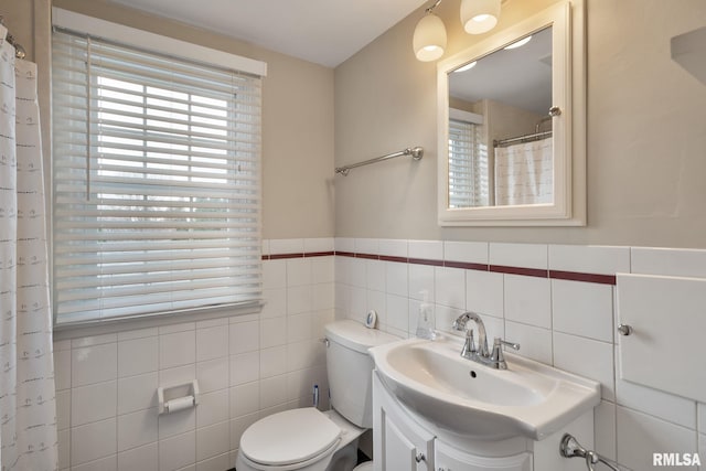 full bathroom featuring toilet, tile walls, vanity, a wainscoted wall, and curtained shower
