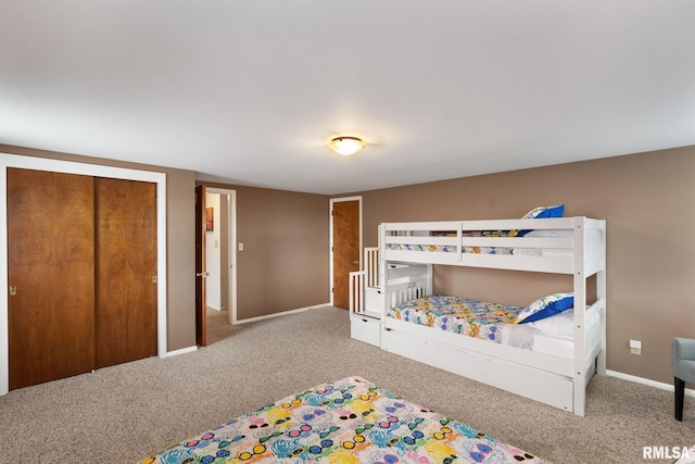 carpeted bedroom featuring baseboards and a closet