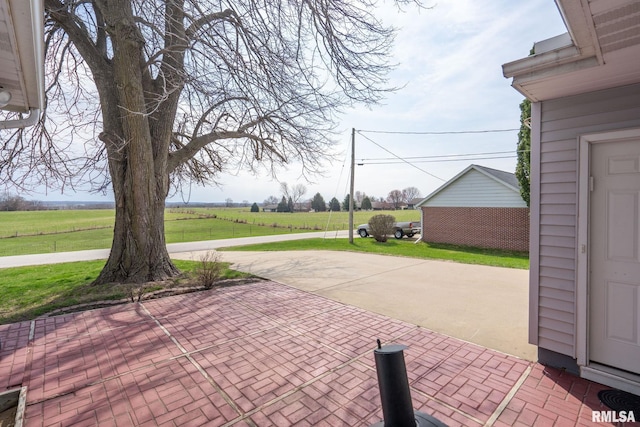 view of patio with concrete driveway and a view of rural / pastoral area