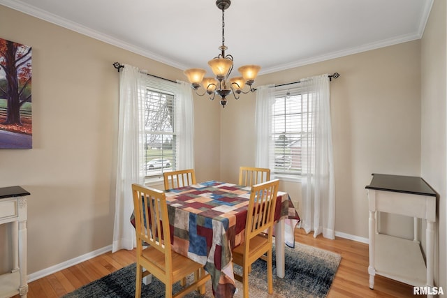 dining area with a chandelier, plenty of natural light, light wood finished floors, ornamental molding, and baseboards