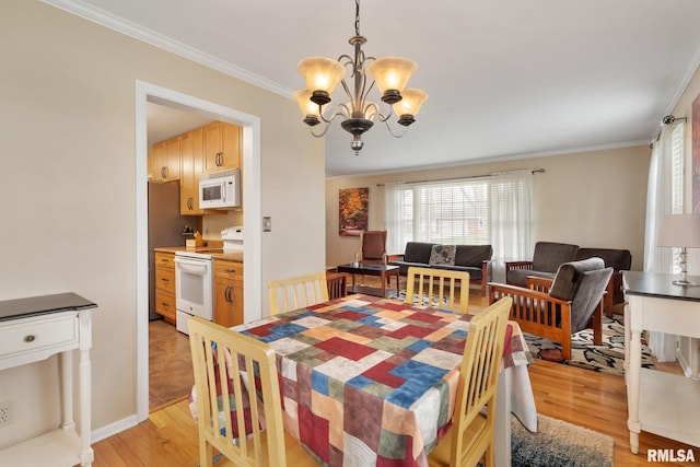 dining room with a chandelier, light wood-type flooring, ornamental molding, and plenty of natural light
