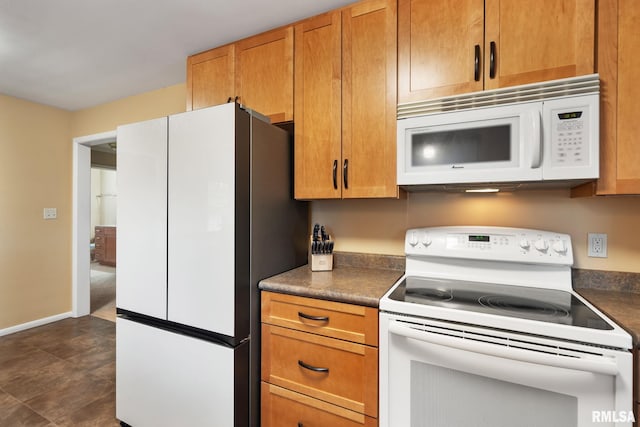 kitchen featuring white appliances, dark countertops, baseboards, and brown cabinets