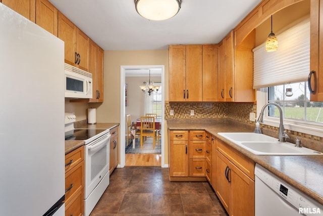 kitchen featuring white appliances, a sink, healthy amount of natural light, and a chandelier