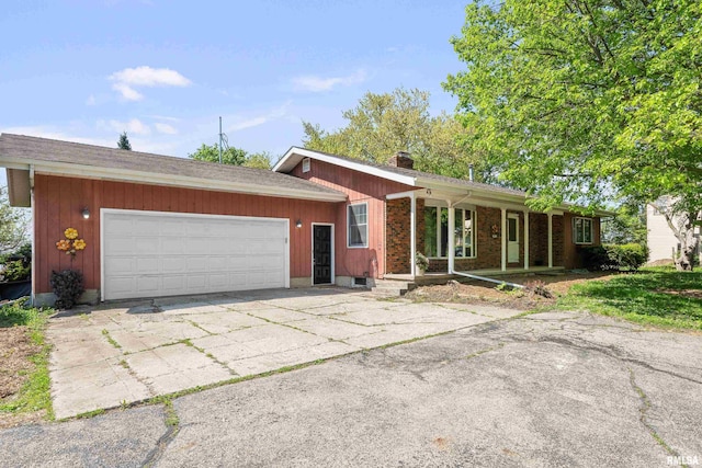 ranch-style home featuring a chimney, a garage, covered porch, and driveway