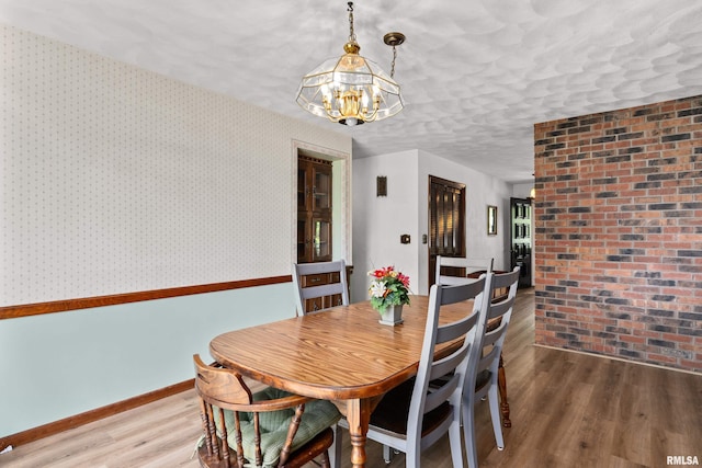 dining room featuring wood finished floors, a chandelier, and baseboards