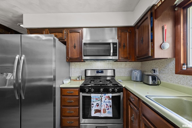 kitchen featuring stainless steel appliances, light countertops, decorative backsplash, and a sink