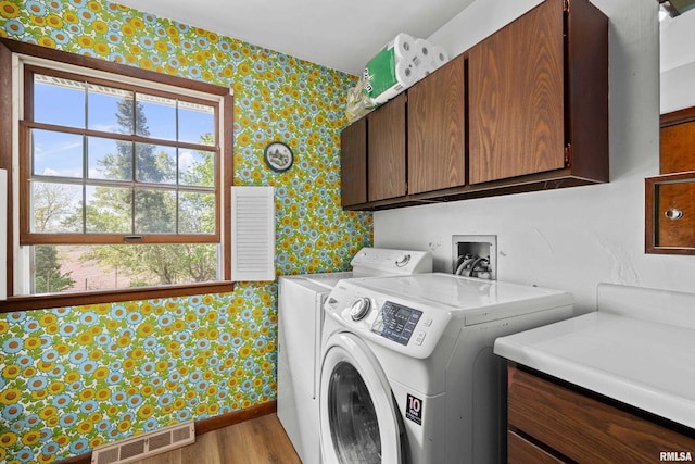 laundry area featuring wallpapered walls, cabinet space, independent washer and dryer, and wood finished floors