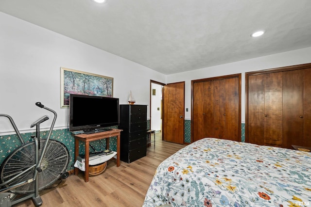 bedroom featuring wood finished floors, multiple closets, and recessed lighting