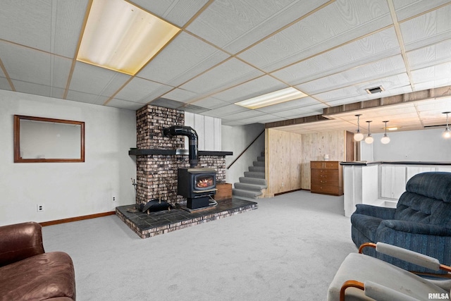 carpeted living area with a wood stove and baseboards