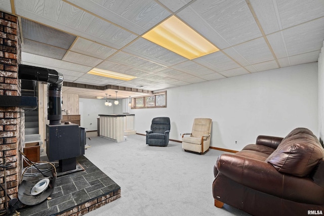carpeted living area with a wood stove and baseboards
