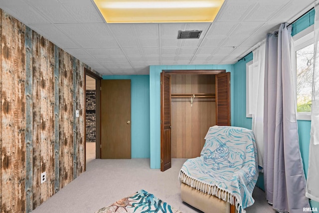 living area with carpet floors and wood walls