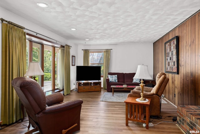 living room featuring wood walls, wood finished floors, recessed lighting, and a textured ceiling