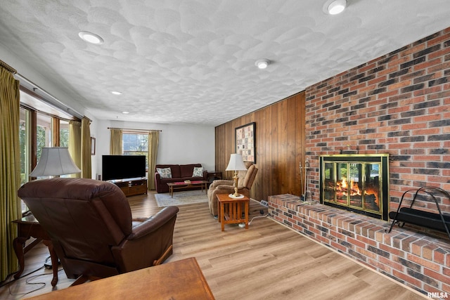 living area with wood finished floors, wooden walls, a fireplace, recessed lighting, and a textured ceiling