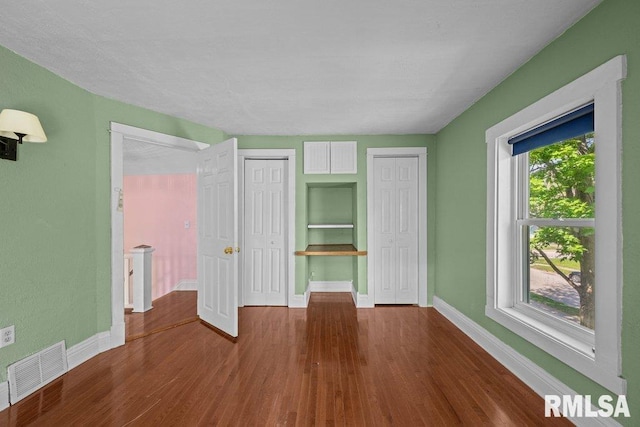2350 Jefferson Ave, Davenport, IA 52803 - unfurnished bedroom with baseboards, wood finished floors, and two closets