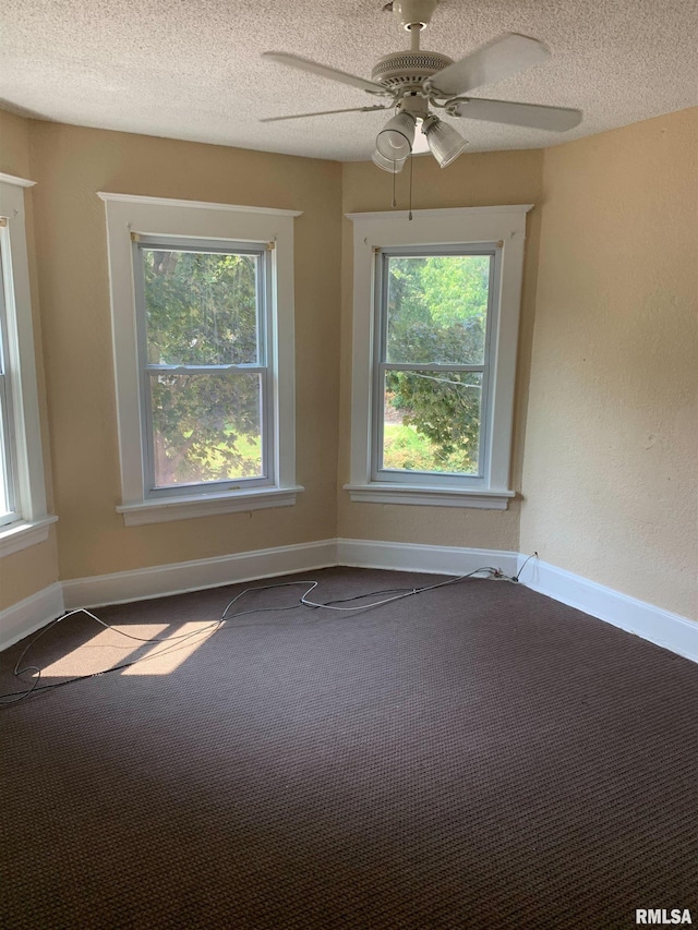 carpeted spare room with plenty of natural light, a textured ceiling, ceiling fan, and baseboards