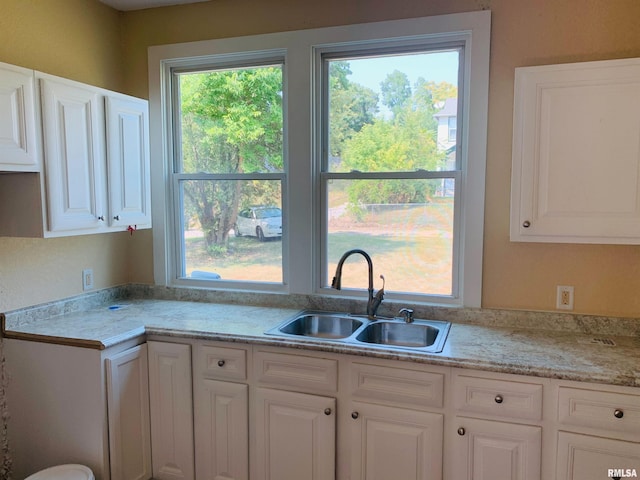 kitchen with a sink, light countertops, and white cabinets