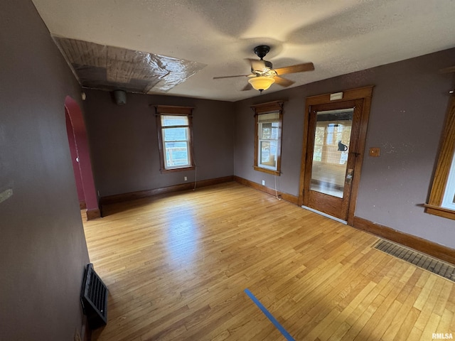 empty room with ceiling fan, light wood-style flooring, baseboards, and a textured ceiling
