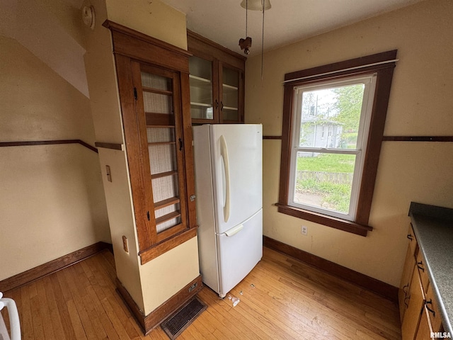 unfurnished dining area featuring light wood-style flooring and baseboards