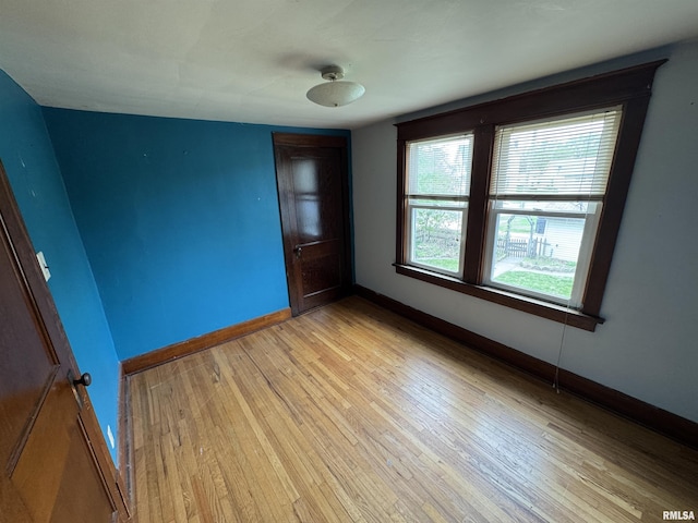 spare room with baseboards and light wood-type flooring