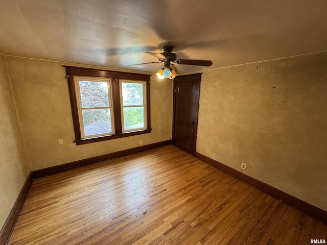 empty room with hardwood / wood-style floors, ceiling fan, and baseboards