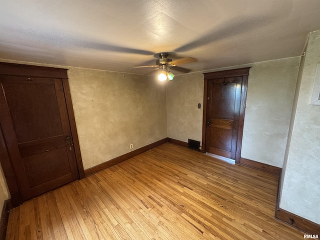 spare room with light wood-style flooring, a ceiling fan, and baseboards