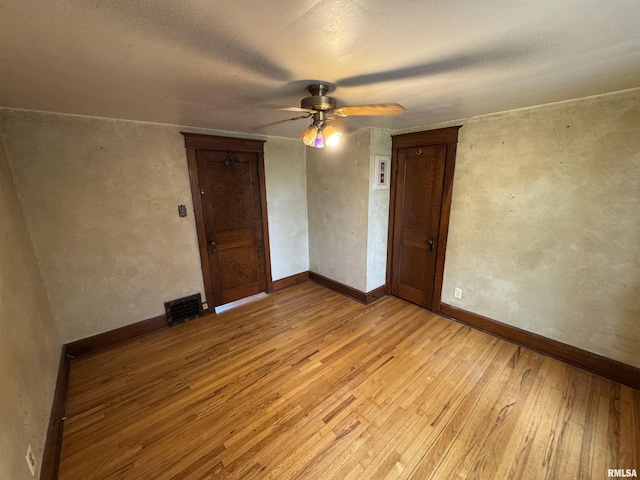 empty room featuring light wood-style flooring, a ceiling fan, and baseboards