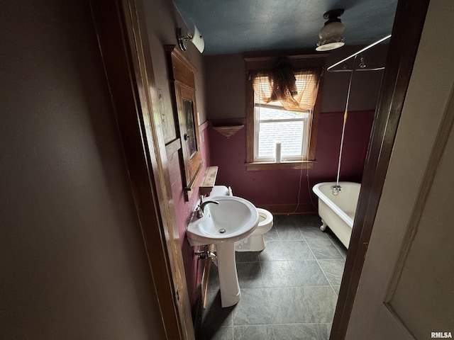 full bathroom featuring a soaking tub, a sink, and tile patterned flooring