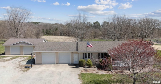 single story home with driveway, an attached garage, and a shingled roof