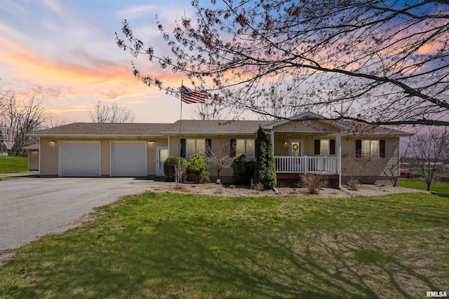 ranch-style house with a porch, an attached garage, asphalt driveway, and a lawn
