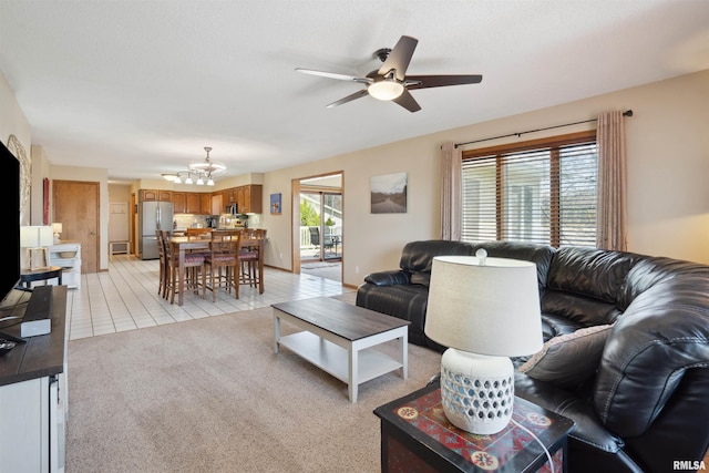 living room featuring a chandelier, a ceiling fan, light tile patterned floors, and light colored carpet
