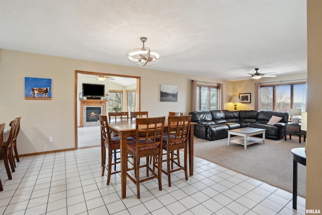 dining room featuring a ceiling fan, light colored carpet, and a glass covered fireplace