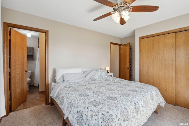 carpeted bedroom featuring a closet, a ceiling fan, and ensuite bath