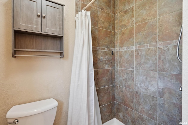 bathroom featuring a tile shower and toilet