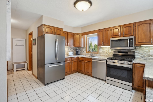 kitchen featuring stainless steel appliances, light countertops, backsplash, and brown cabinets