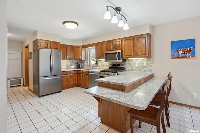 kitchen featuring appliances with stainless steel finishes, light countertops, a peninsula, and tasteful backsplash