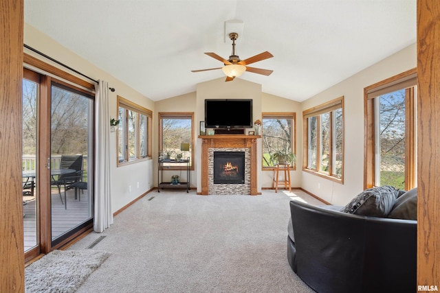carpeted living room with baseboards, lofted ceiling, a ceiling fan, and a tiled fireplace