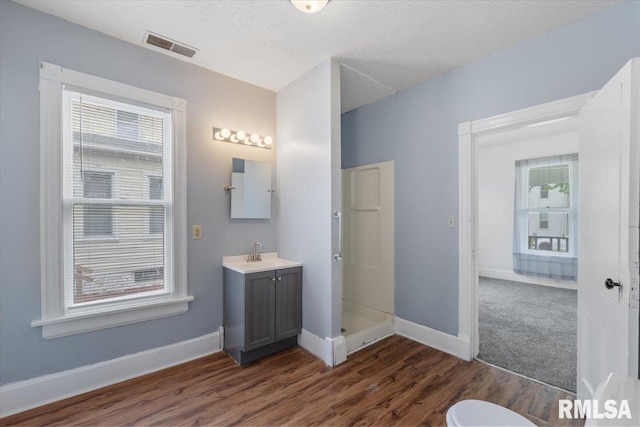 720 Wilkes Ave, Davenport, IA 52802 - bathroom with wood finished floors, a shower stall, baseboards, vanity, and a textured ceiling