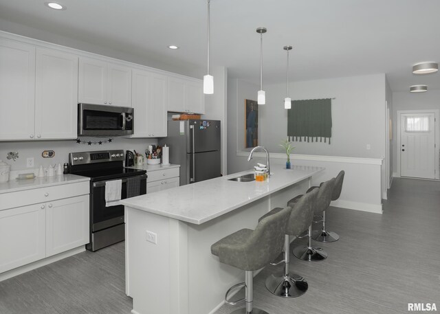 6811 Genesis Way, Bettendorf, IA 52722 - kitchen featuring stainless steel appliances, a sink, wood finished floors, a kitchen bar, and recessed lighting