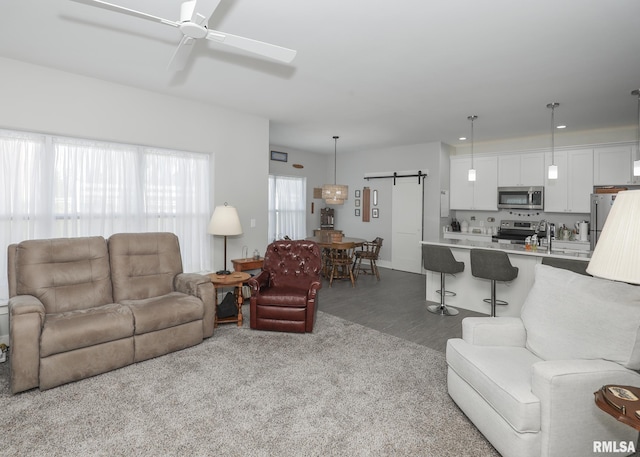 6811 Genesis Way, Bettendorf, IA 52722 - living room featuring a barn door, a ceiling fan, dark colored carpet, and dark wood-style floors